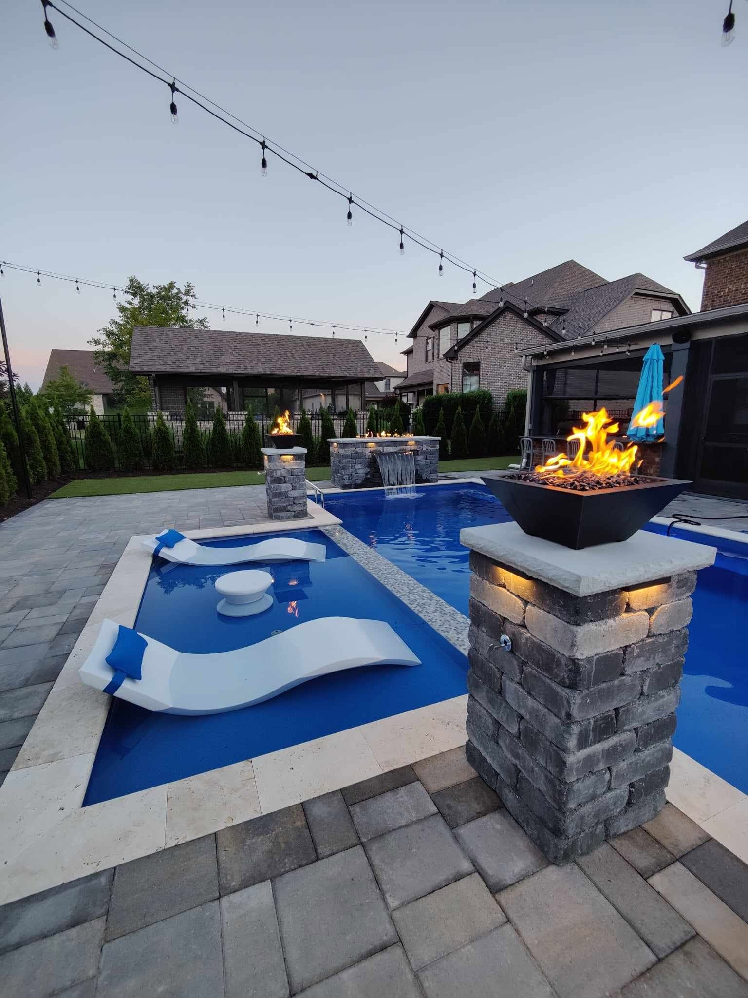 custom pool with fire features and sun loungers